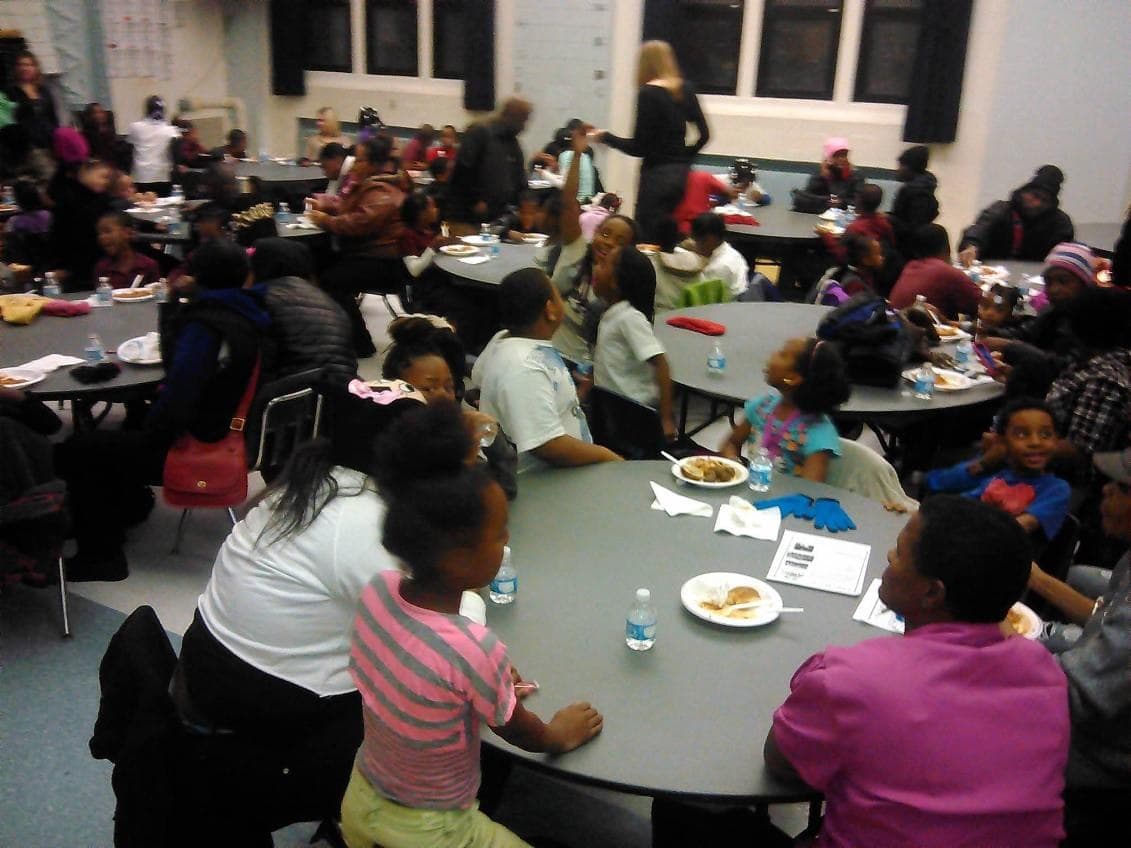 Families and students eating together at round tables in a school cafeteria
