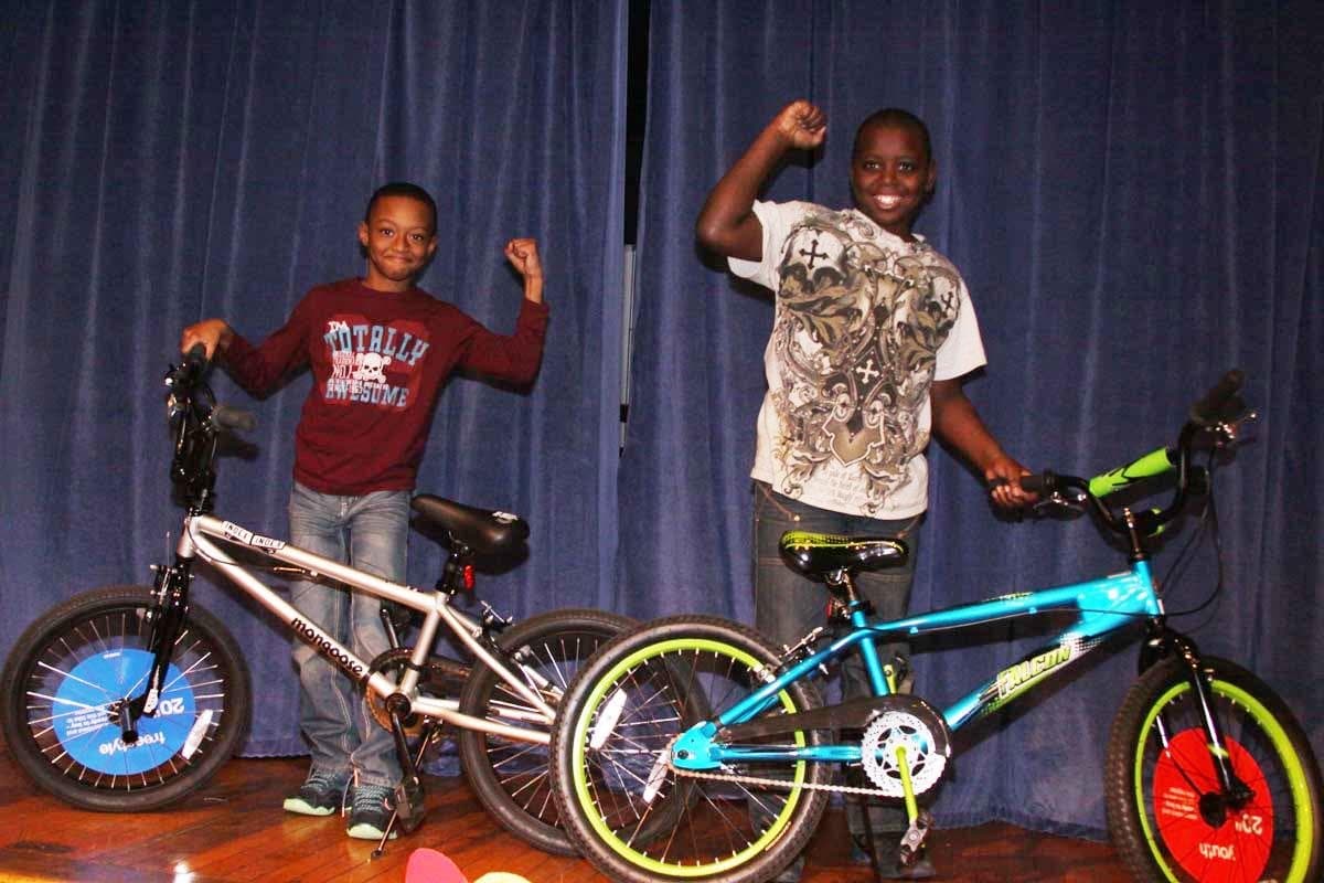 Two boys celebrating with new bikes on a stage