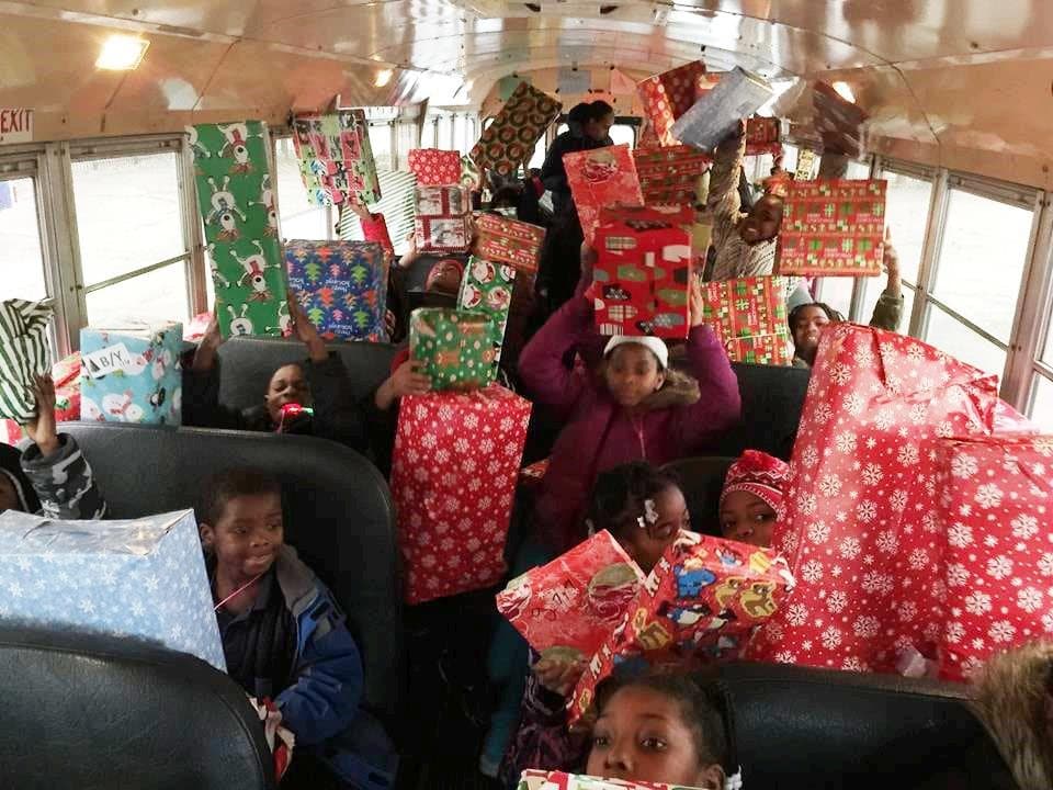 A bus full of kids holding wrapped presents