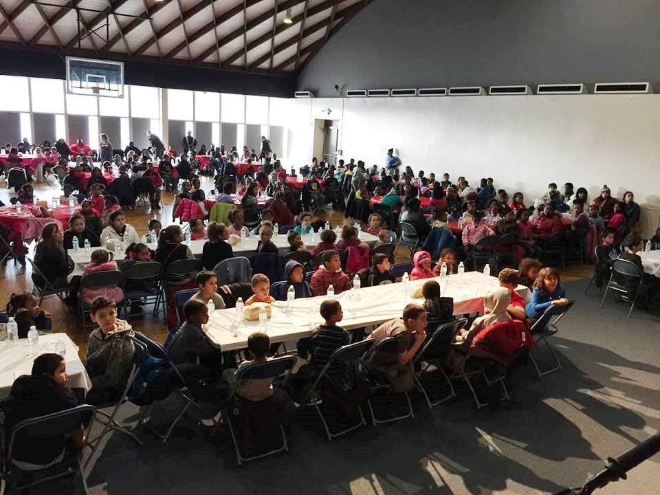 A full hall of families sharing a holiday meal