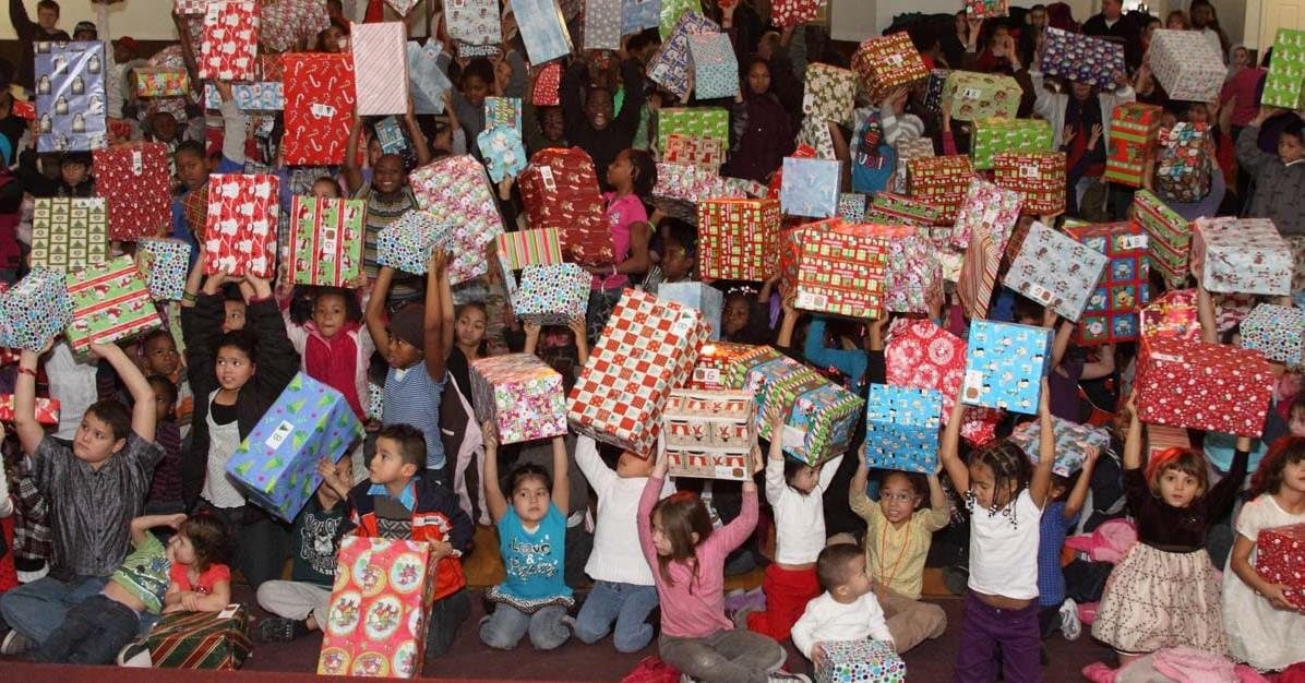 A room full of kids holding up their presents