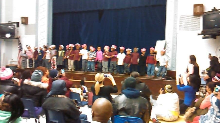 Students performing on a school stage while families watch