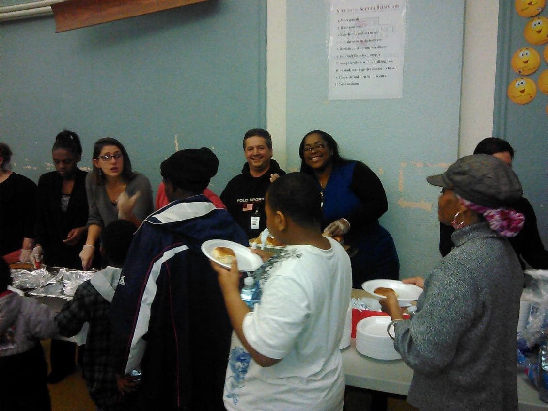 Smiling volunteers serving food to families at a school event