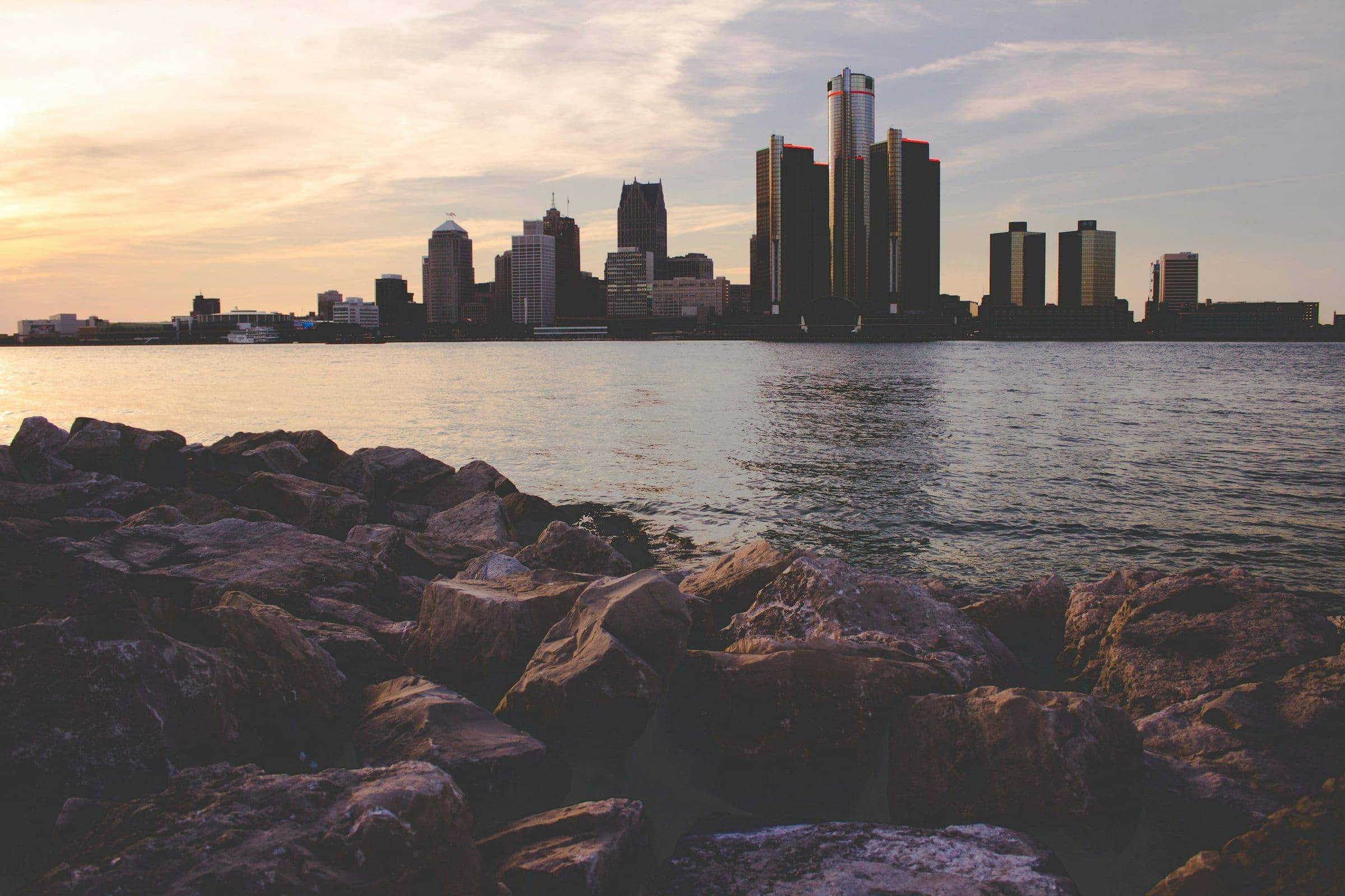 Detroit skyline at dusk from a rocky shoreline